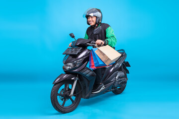 Young Male Courier on Scooter Carrying Paper Shopping Bags on Studio Shot Over Blue Backdrop