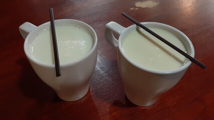 Two glasses of fresh milk on a wooden table. Products from Moeria Milk or Susu Moeria in Kudus, Central Java, Indonesia.