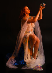 Fantasy studio portrait of a red-haired mermaid faery model wearing a white pearl gown, fairytale...