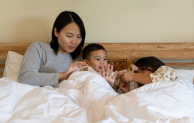Happy family playing on bed in hotel bedroom