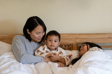 Happy family playing on bed in hotel bedroom