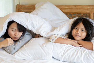 Happy family posing under blankets in a hotel bedroom