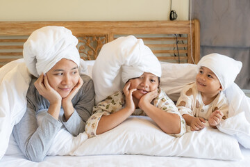 A family with heads wrapped in towels and blankets lie on a hotel bedroom. World Tourism Day.