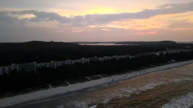 Sunset over Prora beach on R&uuml;gen island, with golden skies above the sea and the iconic buildings lining the shore.