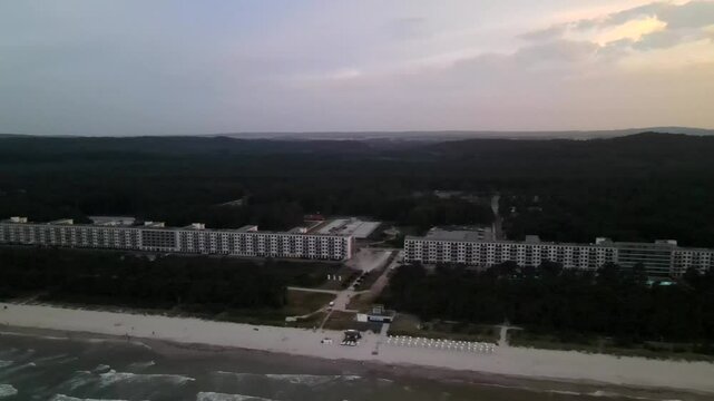 Golden sunset at Prora beach on R&uuml;gen, with waves rolling in and the historic seaside complex lining the tranquil coast.