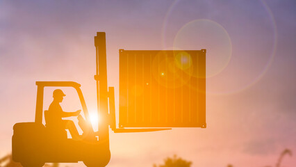 Silhouette of forklift lifting container box blur background