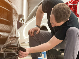 A car wrapping specialist applies a polyurethane film to the car. Selective focus. PPF protective...