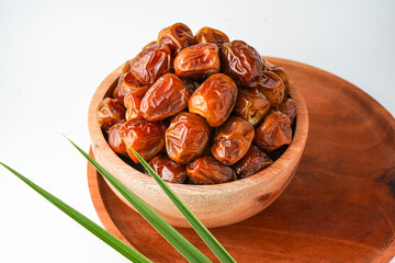 Dates fruit sukari or kurma sukari, in wooden bowl isolated on white background