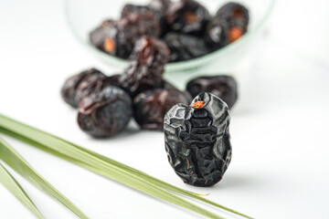 Dates fruit ajwa or kurma ajwa, in bowl isolated on white background