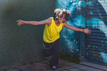 smiling young man with headphones dancing in the street