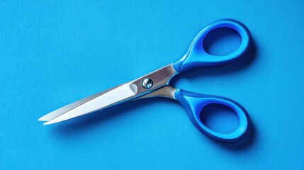 Blue plastic-handled scissors on a vibrant blue surface