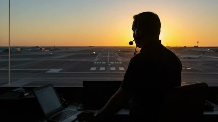 Silhouette of a Male Air Traffic Controller in a Control Tower Overlooking an Airport Runway at Sunset, Managing Flight Operations in a Busy Aviation Hub