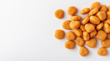 An overhead shot showcases a pile of crunchy brown dry dog food bits of various shapes, including round and heart shapes, against a plain white background, viewed close.