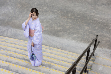 階段の上に立つ着物を着た若い日本人女性