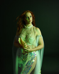 Fantasy studio portrait of a red-haired mermaid faery model wearing a white pearl gown, fairytale...