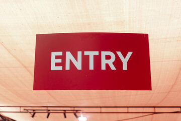 Red "ENTRY" signboard hanging from the ceiling at an indoor location, indicating the entrance area.