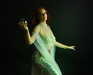 Fantasy studio portrait of a red-haired mermaid faery model wearing white pearl gown, fairytale...