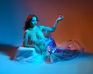 Fantasy studio portrait of a red-haired mermaid faery model wearing white pearl gown, fairytale...