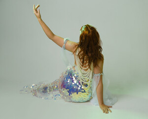 Fantasy studio portrait of a red-haired mermaid faery model wearing white pearl gown, fairytale...