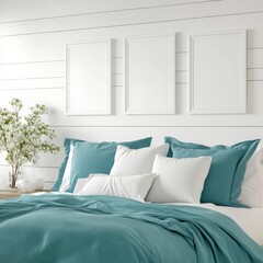 Teal bedding and pillows on a bed in a bright bedroom with white walls and white framed pictures. A small flowering plant sits on a side table.