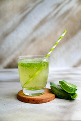 Fresh aloe vera drink in glass cup with aloe slices 