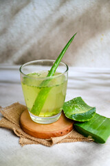 Fresh aloe vera drink in glass cup with aloe slices 