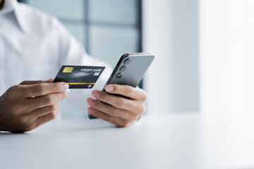 Asian male hold credit card and use mobile phone for online transactions