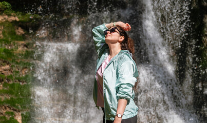 Young  Woman standing in front of spring waterfall 