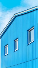 Blue industrial building facade with 3 windows against a bright sky showcasing minimalist architecture and clean lines for modern design projects