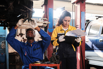 Latino female inspector engineer discussing Black male mechanic, coworker about maintenance service works at fix car garage, professional worker jobs in automotive and transportation industry business