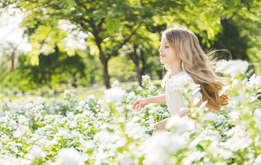 Fototapeta premium Little girl playing in the garden with morning sunrise