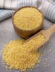 Millet groats in bowl and scoop on a gray background