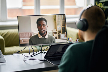 Business meeting through video call, featuring a professional male on laptop screen while colleague...