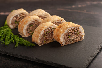 Savory fish rolls with herbs served on a dark slate board ideal for gatherings or casual meals