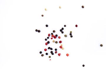 Close-up of peppercorns - red, green, black and white, scattered chaotically on a white background, aromatic spice, macro photography.