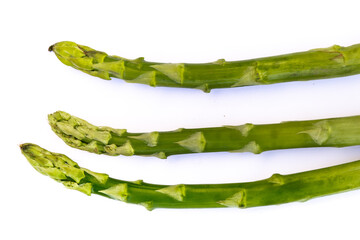 Fresh green asparagus stalks laid out horizontally on white background