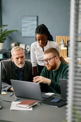 Multiracial business team comprising two men and a woman collaborating on a project in modern...