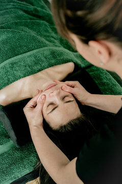 Young woman massagist making lifting face massage