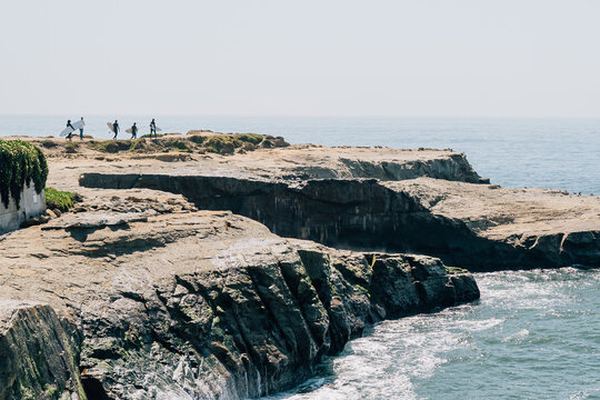 Surfers carrying surfboards across rocky walkway