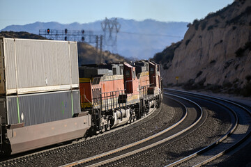 Obraz premium Orange locomotive engines pulling stacked shipping containers