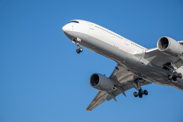 Airbus A350-900 white flying overhead in clear blue sky