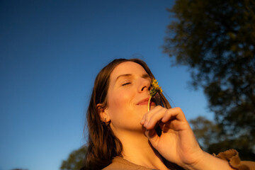 Woman holding dandelion flower in warm golden sunlight