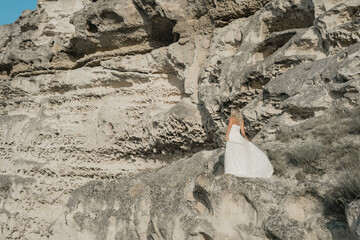 a woman in a white dress, a bride on a mountain with a blue sky. Beautiful nature, freedom, enjoyment of life. High quality photo