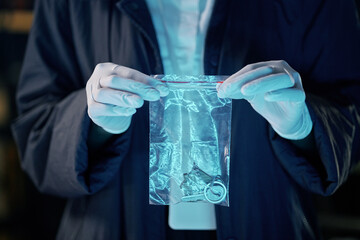 Gloved hands carefully handling evidence bag containing keychain during investigation inside laboratory setting with focus on evidence bag and keychain