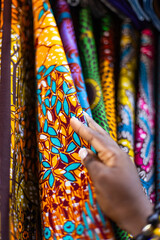 Small business owner of an African Print, Ankara fabric shop proudly displaying different kinds of...