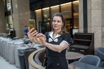 A business lady takes a selfie in front of a restaurant