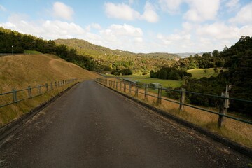 Road atop Huia Dam surrounded by lush New Zealand bush