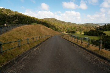 Road atop Huia Dam surrounded by lush New Zealand bush