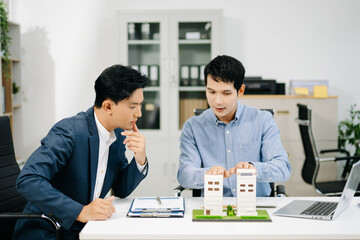 Two professional men analyzing house model and design layout in office. Ideal for themes of architecture, investment, real estate, property
