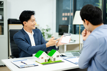 Real estate agent consulting with buyer on house model and pricing using calculator in modern office. and client service.